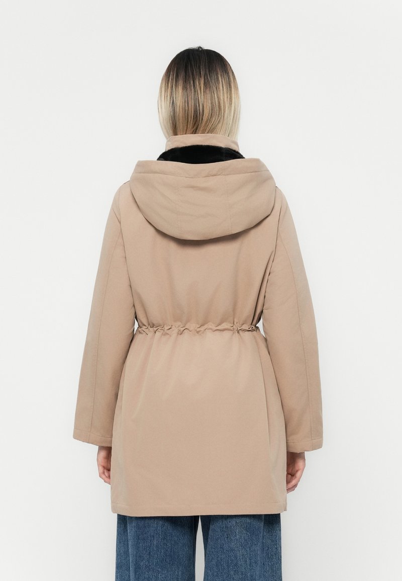 Beżowa kurtka z kapturem, z wcięciem w talii, długimi rękawami i miękką czarną podszewką. Gładka tekstura, casualowy design i średniej długości krój.