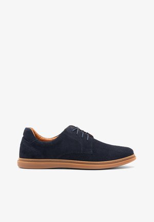 Scarpe in suede blu navy con dettagli perforati, suola in gomma marrone chiaro e lacci abbinati. L'interno presenta una fodera di contrasto marrone.