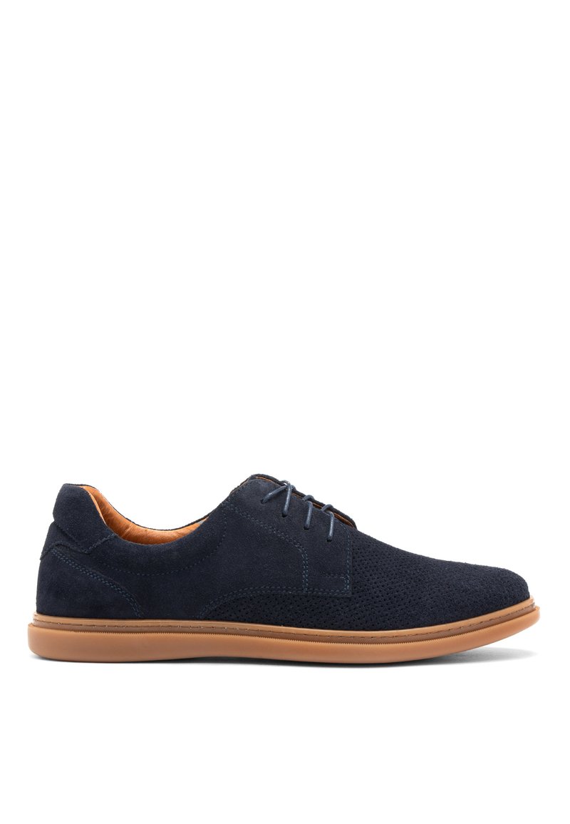 Zapatos de ante azul marino con detalles perforados, suela de goma marrón claro y cordones a juego. El interior presenta un forro marrón en contraste.