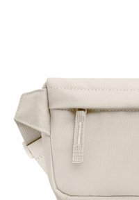 Leinenbeutel in hellem Beige mit einem umklappbaren Deckel, der eine strukturierte Oberfläche aufweist, sowie einem seitlichen Riemen mit einer kleinen hängenden Lasche.