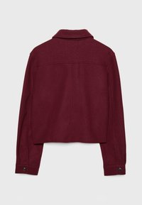 Bordeaux uldblandingsjakke med cropped design, knaplukning ved ærmerne og klassisk krave. Glat tekstur med synlige syninger.