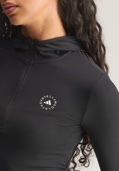 Black long-sleeve athletic top with a high neckline, featuring a zip and a circular logo in white on the chest. Smooth texture.