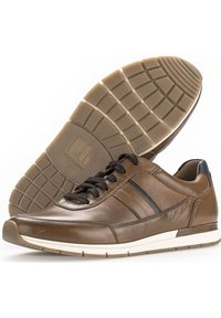 Bruine leren sneakers met zwarte accenten, ronde neus, contrasterende witte tussenzool en een geprofileerde rubberen buitenzool met een ruitpatroon.