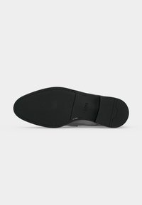 Semelle élégante en cuir noir pour chaussure habillée avec marquage BOSS, bout pointu et bords cousus lisses sur un fond clair.