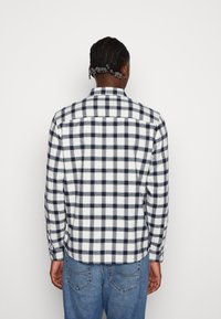 Camicia a maniche lunghe, a quadri, caratterizzata da una fantasia a check blu navy e bianco, realizzata in flanella con colletto dritto, polsini con bottoni e orlo curvo.