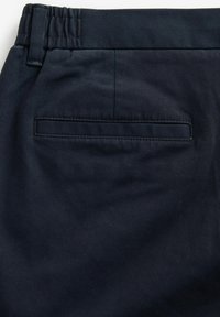 Pantaloni de culoare bleumarin închis, cu o textură netedă, țesută; dispun de un brâu elastic și o singură buzunar la spate cu o clapetă cusută.