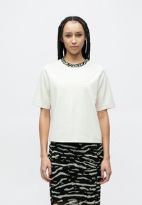 Balti trumpomis rankovėmis marškinėliai su juodai baltu zebros dryžuotu apykakliu, derinami su aptempta juodai balta zebros rašto suknele.