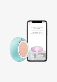 Turkis blå silikon renseapparat med en rund, pink midtpunkt og sølvkant, ved siden av en smarttelefon som viser tilkoblingsinstruksjoner.