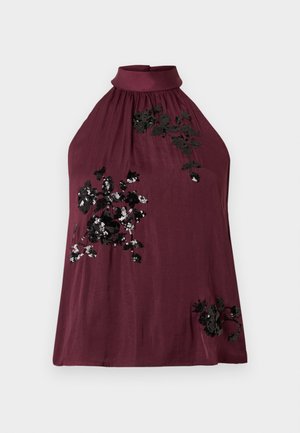 Burgundský top na krk z mäkkej látky, zdobený čiernou kvetinovou výšivkou s flitrami na prednej strane a zožmýkaným výstrihom.