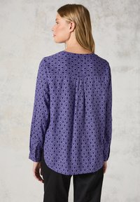 Blusa viola a fantasia con motivo a diamante, maniche lunghe, orlo arrotondato e un delicato dettaglio di piega sul retro.