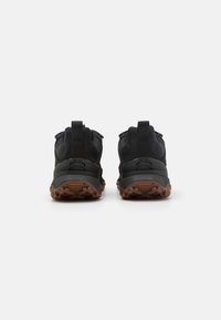 Chaussures de randonnée noires avec un tissu texturé et des accents en caoutchouc. Elles disposent d'une semelle robuste et d'une languette à l'arrière pour un enfilage facile.