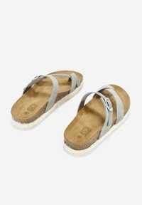 Sandalias de ante gris con dos correas cruzadas, una suela plana estilo esparto y un detalle de hebilla metálica en una de las correas.