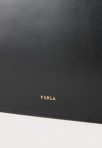 Duas carteiras de couro preto com uma textura suave, logotipo "Furla" em dourado gravado e costura em contraste ao longo das bordas.