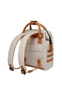 Beige fabric backpack with brown leather accents, padded straps, a top handle, and a zip closure. Features horizontal straps on the side.