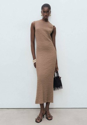 Brown textured midi dress with a fitted silhouette, asymmetrical neckline, and sleeveless design. Accessorized with a black woven handbag.