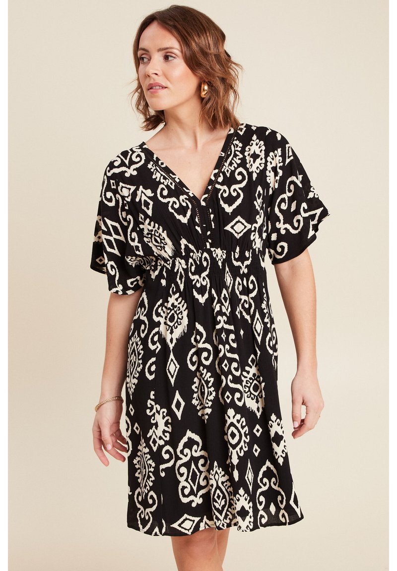 Schwarzes und weißes gemustertes Kleid mit kurzen Ärmeln, tiefem V-Ausschnitt, elastischem Taillenbund und fließendem Rock mit komplizierten Designs.