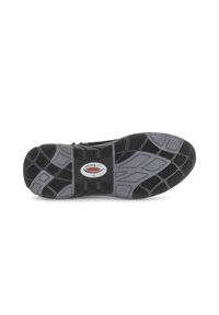 De zool van de schoen heeft een gepatineerde zwarte rubberen basis met grijze accenten en een circulair logo. Textuur op het loopvlak voor grip en stabiliteit.