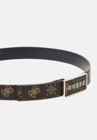 Ceinture en cuir noir avec une boucle ornée d'or, arborant un motif de logo marron répété et une texture lisse. Taille ajustable pour le confort.