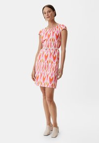 Kurzes Kleid mit einem bunten Herzmuster in Pink und Orange, tailliert mit einem weißen Gürtel, aus leichtem Stoff gefertigt.