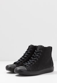 Black high-top shoes made of suede with a textured finish. Features round toe, contrasting rubber sole, and lace-up front.