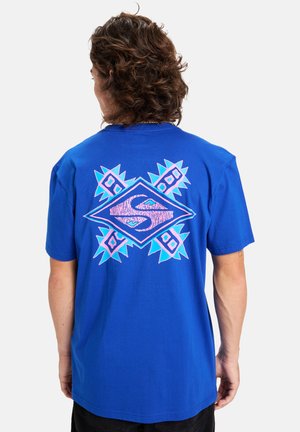 Blaues Baumwoll-T-Shirt mit einem großen geometrischen Grafikdesign in Pink und Türkis auf der Rückseite, mit kantigen Akzenten und einem lockeren Schnitt.