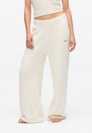 Pantalons de salon blancs, texturés, avec une coupeLoose et une jambe large. Fabriqués en matériau doux, semblable à de la polaire, et comportent un logo brodé subtil sur la taille.