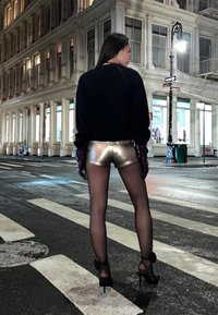 Metallic silver shorts, black long-sleeve top, burgundy gloves, sheer black tights, and high-heeled shoes with floral accents, night street scene.