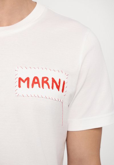 Tricou alb din bumbac, cu un buzunar cusut roșu ce are cuvântul "MARNI" brodat cu litere roșii îndrăznețe. Mâneci scurte și gât în formă de cerc.