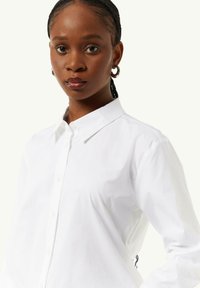 White button-up shirt with a collared neckline, long sleeves, and a smooth texture. Features a small embroidered detail at the back.