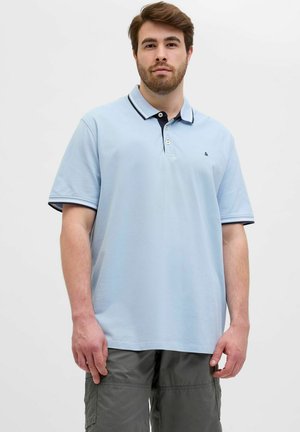 Lyseblå polo med en marineblå krave, to knapper og kontrastkanter. Korte ærmer og en afslappet pasform. Båret med grå cargo shorts.
