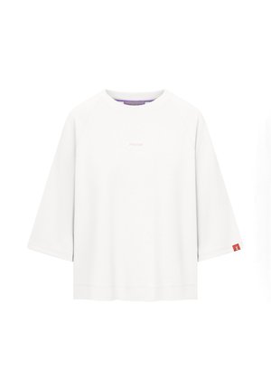 Biała, oversizeowa koszula z długim rękawem i szerokimi rękawami, z małym napisem "FRIEDA" na piersi oraz czerwonym oznaczeniem na mankiecie rękawa.