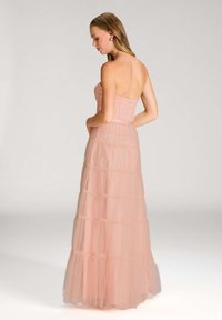 Sangkar pink tanpa tali dengan bodice yang sesuai dan rok tulle berlapis dengan tier berkerut, menampilkan siluet yang mengalir.