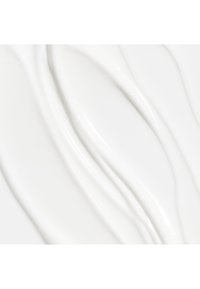 Hvit krem eller lotion med jevn, flytende tekstur og milde bølger. Overflaten ser blank ut og reflekterer lys subtilt.