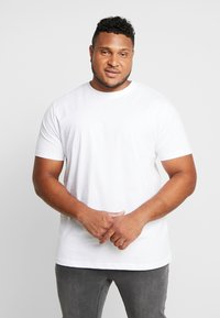 White short-sleeve t-shirt made from cotton, featuring a crew neckline and a relaxed fit, paired with dark gray jeans.