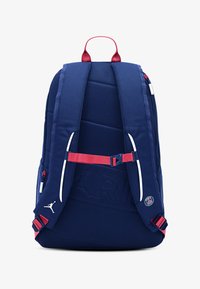 Navy fabric backpack with padded straps and back. Features red accents, white zipper details, and embossed logo on the front.