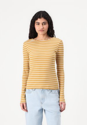 Yellow long-sleeve top with white horizontal stripes, ribbed texture, round neckline, and fitted silhouette, paired with light blue jeans.