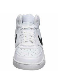 Baskets blanches avec logo Nike noir. Présentent une tige en cuir, un bout perforé et un laçage plat. La semelle intermédiaire est texturée et blanche.