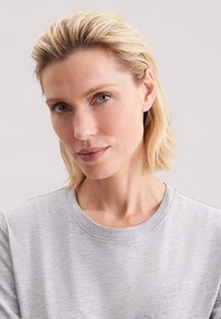 Lysegrå t-shirt med rund halsudskæring og korte ærmer, der har en blød stoftekstur og et minimalistisk design.