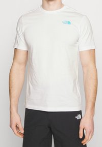 White short-sleeve t-shirt made from cotton with a round neck, featuring a small blue logo on the left chest. Plain design, smooth texture.