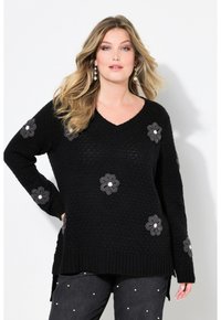 Mustavillattu neulepusero V-kauluksella, jossa on harmaita kukkakoristeita valkoisilla keskiosilla, teksturoitu kuvio ja ribattu helma sekä hihansuut.