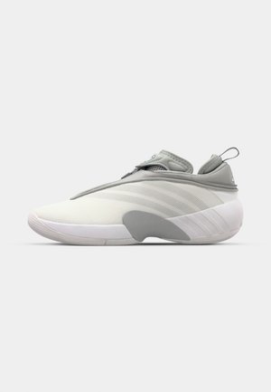 Zapatilla deportiva gris claro con un diseño elegante, que cuenta con una parte superior texturizada, correa elástica y una suela de goma blanca. Marca sutil en la lengüeta.