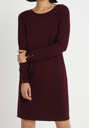 Dunkelrotes Strickkleid mit langen Ärmeln, rundem Ausschnitt und Knopfakzenten an den Manschetten. Glatte Textur, knielang, legere Passform.