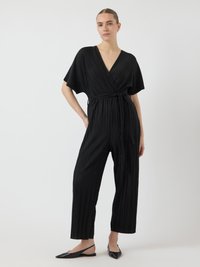 Čierny plisovaný overal s prekríženým dizajnom, výstrihom do V, širokými rukávmi a opaskom v páse. V kombinácii s čiernymi slingback balerínkami.