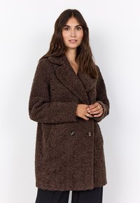 Brauner, doppelt knöpfbarer Mantel aus strukturiertem, flauschigem Material mit Reverskragen und zwei schwarzen Knopfakzenten. Verfügt über Seitentaschen.