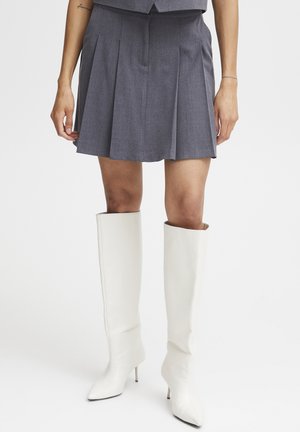 Gray pleated skirt with a high waist and fitted silhouette, paired with tall white heeled boots featuring a ribbed texture and pointed toe.