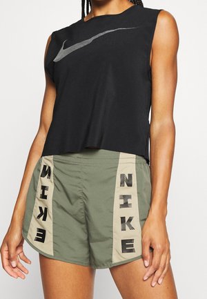 Czarny bezrękawnik z srebrnym logo Nike, zestawiony z oliwkowozielonymi spodenkami z beżowymi panelami i czarnym napisem Nike z przodu po bokach.