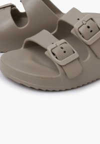 Lys beige sandaler med to justerbare spænder og en tekstureret overflade. Designet med åbne tæer og en tyk sål for komfort.