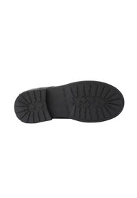 Suela de bota negra con un patrón de relieve profundo y "HECHO EN ESPAÑA" grabado en el centro, aislada sobre fondo blanco.