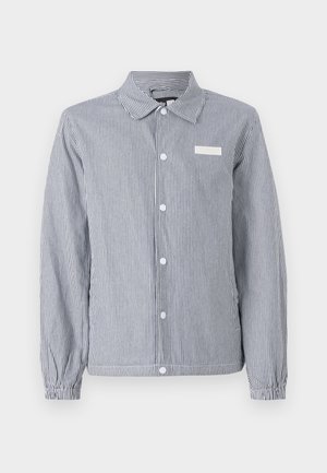 Striped button-up shirt in navy and white, featuring a collar, long sleeves with elastic cuffs, and a small white label on the chest.