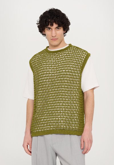 Strick, ärmelloser Pullover in olivgrün mit einem gemusterten, offenen Gewebedesign. Über einem weißen T-Shirt getragen, verfügt er über einen runden Halsausschnitt und gerippte Kanten.